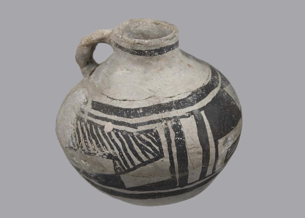 light colored vessel with dark geometric designs, a small opening and a handle